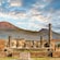 Ancient ruins of Pompeii with Mount Vesuvius in the background under a partly cloudy sky